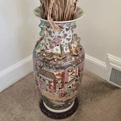 Sale Photo Thumbnail #5: Large vintage Rose Medallion floor vase with applied gilt dragon motifs, displayed on a wooden stand with dried decorative branches.