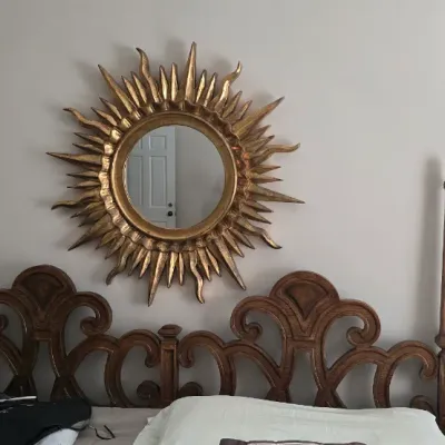 Sale Photo Thumbnail #25: Giltwood style sunburst round mirror mounted above an ornate carved wooden headboard with corner posts.