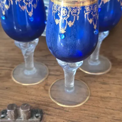 Sale Photo Thumbnail #11: Trio of vintage cobalt blue glass stemmed cordial glasses featuring gold filigree rims and raised blue glass jewel accents.