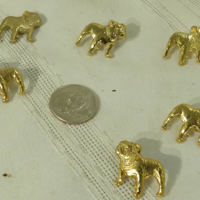 Set of six small gold-tone bulldog pins or charms, shown alongside a coin for scale.