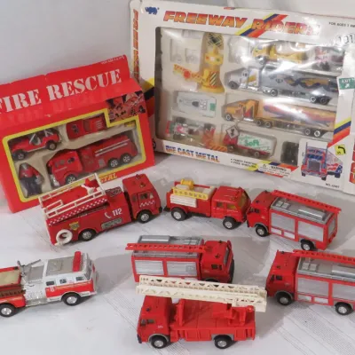 Collection of vintage die-cast toy fire trucks and vehicle playsets, including boxed Fire Rescue and Freeway Riders sets.