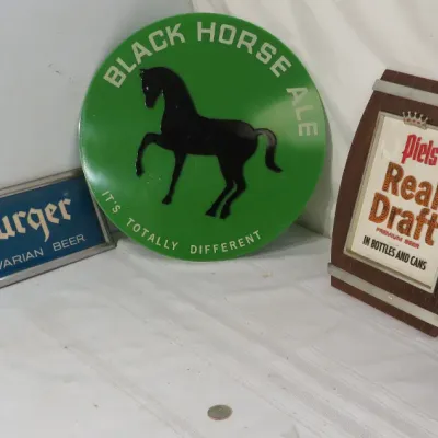 Collection of vintage beer advertising signs including a round green Black Horse Ale sign, a rectangular Würzburger Bavarian Beer sign, a...