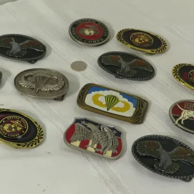 Collection of vintage brass, pewter, and enamel belt buckles featuring military motifs including U.S. Marine Corps insignia, eagles, and...