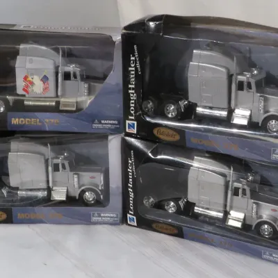 Stack of four New Ray LongHauler Collection die-cast Peterbilt Model 379 semi-truck models in original packaging.