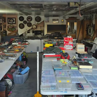 Sale Photo Thumbnail #71: Garage packed with estate sale items including hand tools, power tools, tackle boxes, fishing supplies, and wall decor.