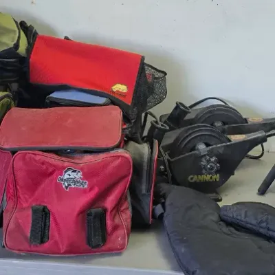 Sale Photo Thumbnail #83: Collection of fishing gear, including various soft-sided tackle bags, fishing rods with reels, a Cannon downrigger, and a landing net.