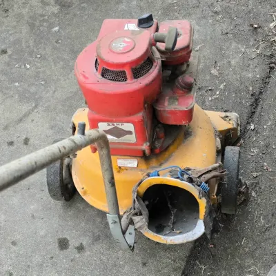Sale Photo Thumbnail #36: Vintage yellow walk-behind lawn vacuum powered by a red 3.5 HP Briggs & Stratton engine, showing heavy wear and dirt from use.