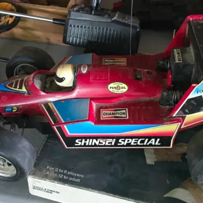 Sale Photo Thumbnail #17: Vintage Shinsei Special Formula 1 remote control racer toy car with transmitter, circa late 1970s to 1980s, showing play wear and dusty surface condition.