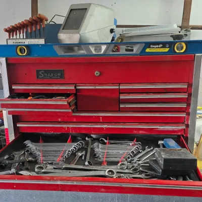 Sale Photo Thumbnail #75: Red Snap-on top chest tool box filled with assorted wrenches and hand tools, topped with a welding helmet, level, and hex key set.
