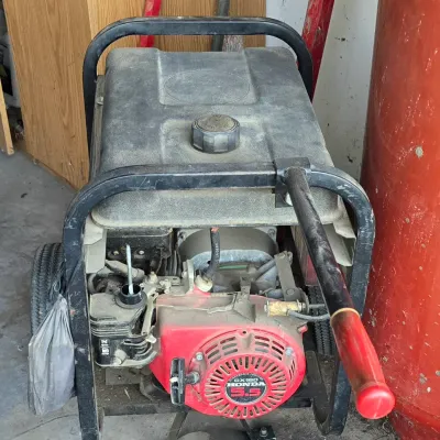 Sale Photo Thumbnail #68: Portable generator powered by a Honda GX160 5.5 HP engine, mounted on a wheeled metal frame with a pull-handle.
