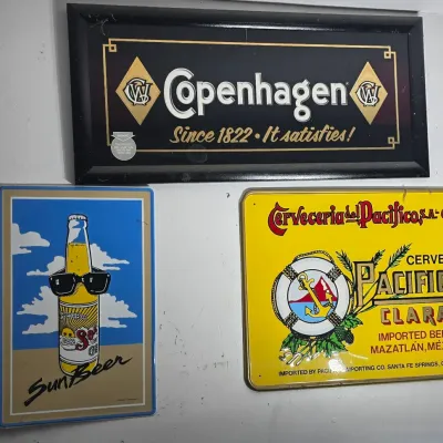 Sale Photo Thumbnail #74: Collection of three advertising wall signs, including a framed Copenhagen snuff mirror and metal beer signs for Sun Beer and Pacifico Clara.