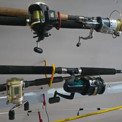 Sale Photo Thumbnail #52: Collection of fishing rods equipped with various spinning and baitcasting reels mounted on ceiling storage hooks.
