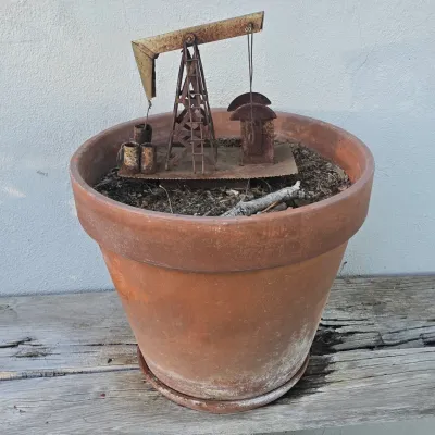 Sale Photo Thumbnail #91: Miniature rusted metal oil derrick sculpture displayed inside a large terracotta planter pot.