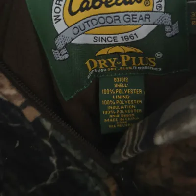 Sale Photo Thumbnail #28: Cabela's Dry-Plus outdoor gear camouflage jacket showing the internal brand and care label.