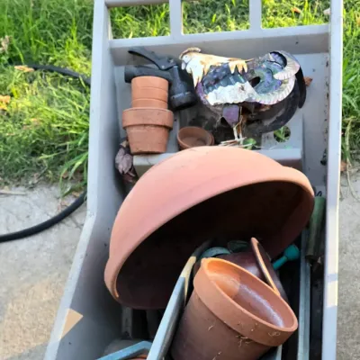 Sale Photo Thumbnail #93: Plastic garden utility cart filled with assorted terracotta planters, plastic planter boxes, garden tools, and decorative garden lawn ornaments.