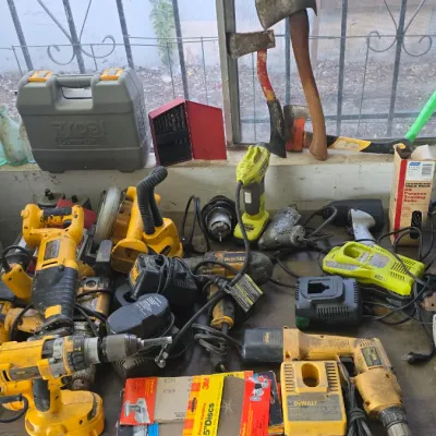 Sale Photo Thumbnail #73: Assortment of power tools including DeWalt and Ryobi cordless drills, battery chargers, a reciprocating saw, and hand tools.