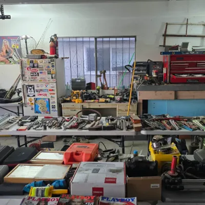Sale Photo Thumbnail #4: Garage workshop sale filled with hand tools, power tools, red tool chests, hard cases, vintage posters, and fishing equipment.
