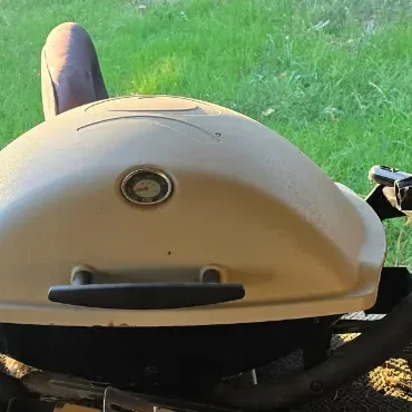 Sale Photo Thumbnail #87: Portable Weber Q series liquid propane gas grill with fold-out side tables and built-in thermometer.