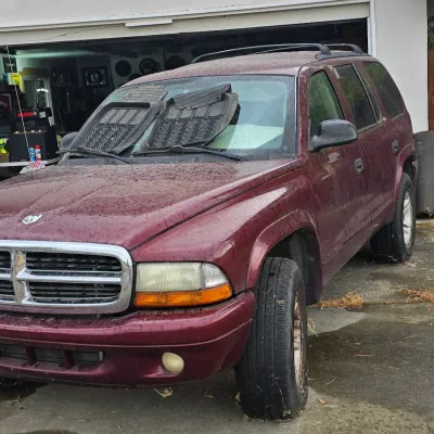 Sale Photo Thumbnail #118: Maroon late 1990s or early 2000s Dodge Durango SUV parked in front of an open garage.