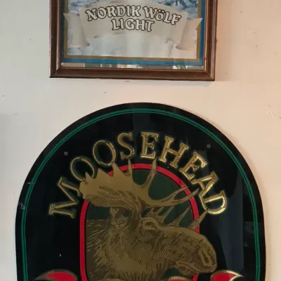 Sale Photo Thumbnail #108: Pair of vintage beer signs, including a framed Nordik Wölf Light mirror with wolf graphics and an oval Moosehead Canadian Lager on Tap wall plaque.