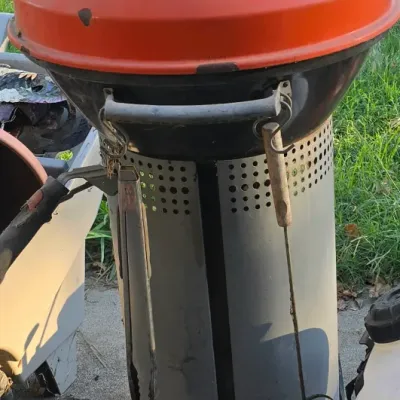 Sale Photo Thumbnail #95: Stök portable orange charcoal grill featuring a pedestal base and built-in thermometer, showing light exterior wear.