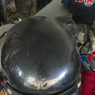 Sale Photo Thumbnail #23: Vintage black Vector motorcycle helmet with snap-on visor and winged logo emblem, showing scuffs and surface wear.