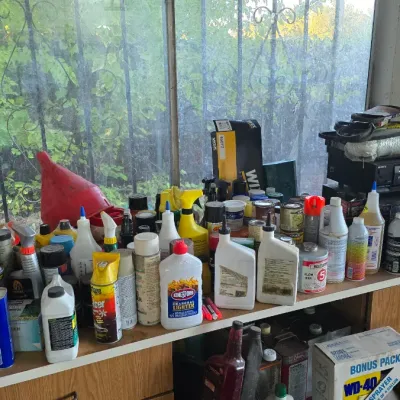 Sale Photo Thumbnail #55: An assortment of workshop and household chemicals, including Klean-Strip acetone, Kingsford charcoal lighter fluid, automotive fluids, spray cans, and various hand tools, arranged on a windowsill and counter space.
