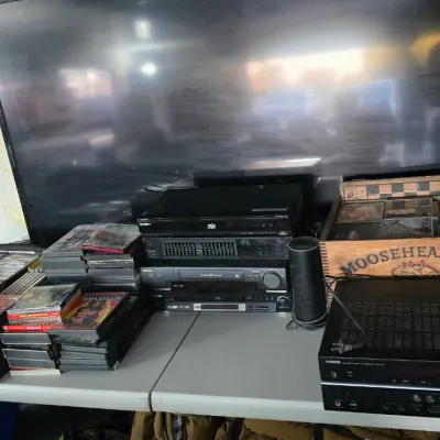 Sale Photo Thumbnail #47: Home entertainment setup including a large flat-screen television, Yamaha receiver, Sony Blu-ray player, media components, stacks of DVDs, and a wooden Moosehead Beer crate filled with cassette tapes.