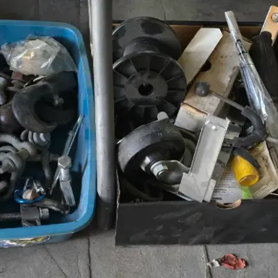 Sale Photo Thumbnail #10: Collection of hardware supplies including heavy-duty shackles, hooks, casters, and miscellaneous tools, alongside canvas duffel and tool bags.