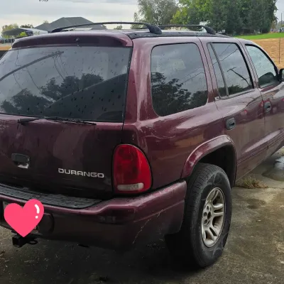 Sale Photo Thumbnail #119: Maroon Dodge Durango SLT SUV parked on a concrete driveway with roof rack and rear trailer hitch.