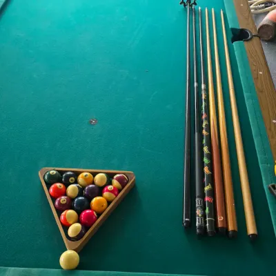 Sale Photo Thumbnail #112: Full-size pool table with green felt top, wood laminate rails, triangular rack with billiard balls, cue ball, and several pool cues.
