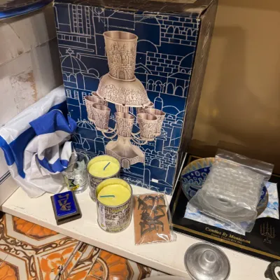 Vintage boxed metal kiddush cup fountains and assorted Judaica items displayed on a shelf.