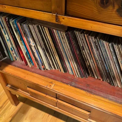 Large collection of vintage vinyl LP records housed inside a rustic wooden cabinet with drawers.