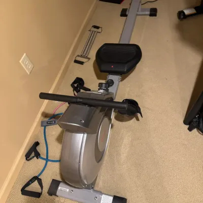Sunny Health & Fitness magnetic rowing machine with adjustable resistance, shown with various fitness accessories.