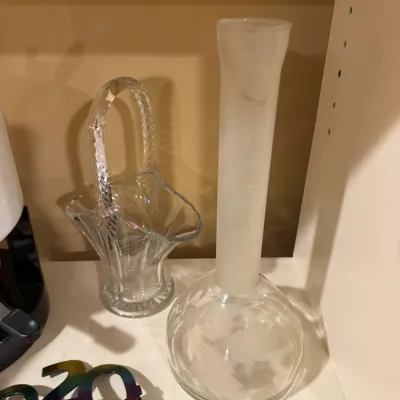Pair of decorative glassware pieces featuring a clear lead crystal basket with an overhead handle and a frosted-neck etched crystal bud...