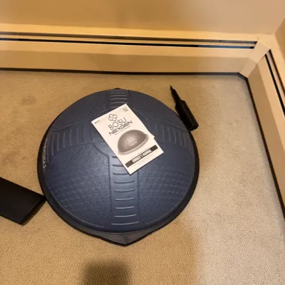 BOSU NexGen Pro Balance Trainer in blue and black, featuring textured quadrant design. Includes owner's manual and hand air pump.