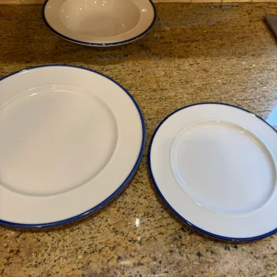 Three-piece white ceramic dinnerware set featuring a dark blue band along the rims, including two plates and one bowl.