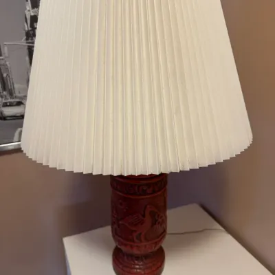 Vintage table lamp featuring a carved reddish-brown wood body with avian motifs topped with a large cream pleated lampshade.
