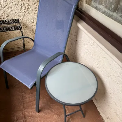 Blue mesh high-back patio armchair paired with a matching small round glass-top side table.