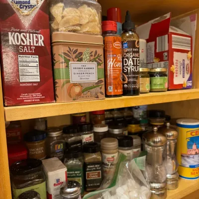 Pantry shelf filled with various spices, seasonings, salt, tea tins, and specialty food items.