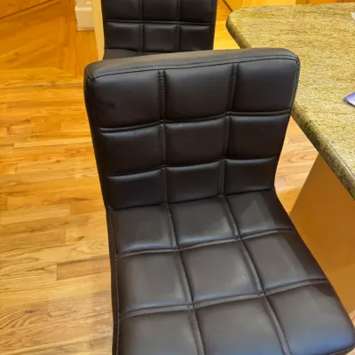 Pair of modern adjustable bar stools with tufted dark brown faux leather upholstery and chrome bases.