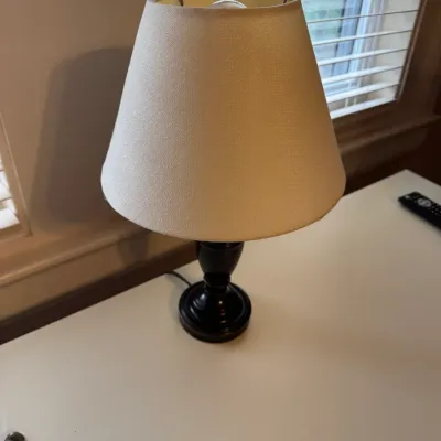 Small table lamp with a dark bronze-tone urn base and a tapered cream fabric shade.