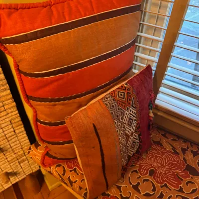Two accent pillows with Kilim and geometric patterned textiles resting on a patterned window seat cushion.