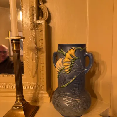 Roseville Pottery Freesia blue double-handled vase, circa 1945, set alongside a vintage brass candlestick.