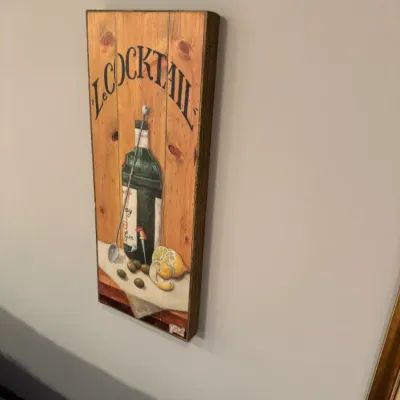 Vertical wooden bar sign with painted cocktail motif featuring gin, olives, and lemons under the text "Le Cocktail".