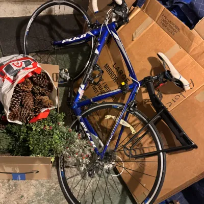 Blue and silver Fuji road bike with drop handlebars and a rear cargo rack, resting against cardboard boxes.