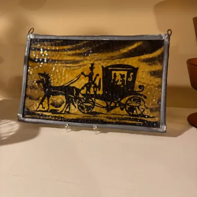 Vintage stained glass suncatcher featuring a black silhouette of a horse-drawn carriage on amber textured glass, framed in lead with...
