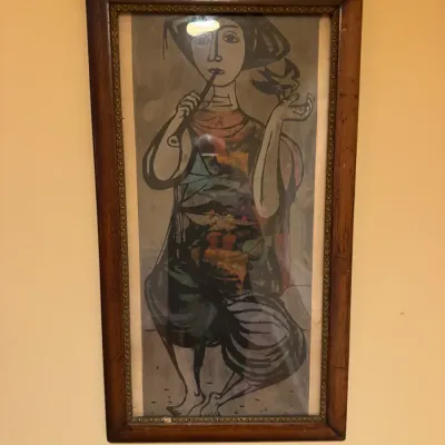 Framed mid-century modern art print depicting a stylized figure playing a pipe with a bird perched on their hand, presented in a dark...