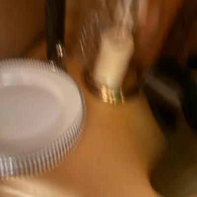 Blurry view of tabletop household goods, including a white plate with a ribbed border and a candle holder.