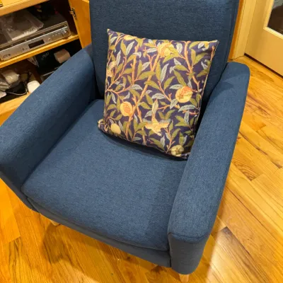 Contemporary blue upholstered armchair paired with a William Morris style botanical throw pillow.